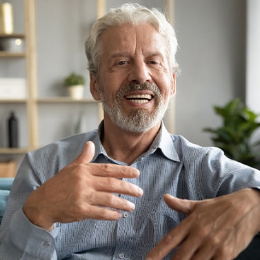 An older man speaking while sitting on a couch