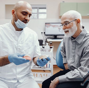 A dentist showing dentures to his patient