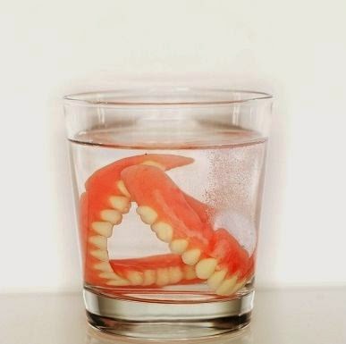 set of dentures in a glass of water